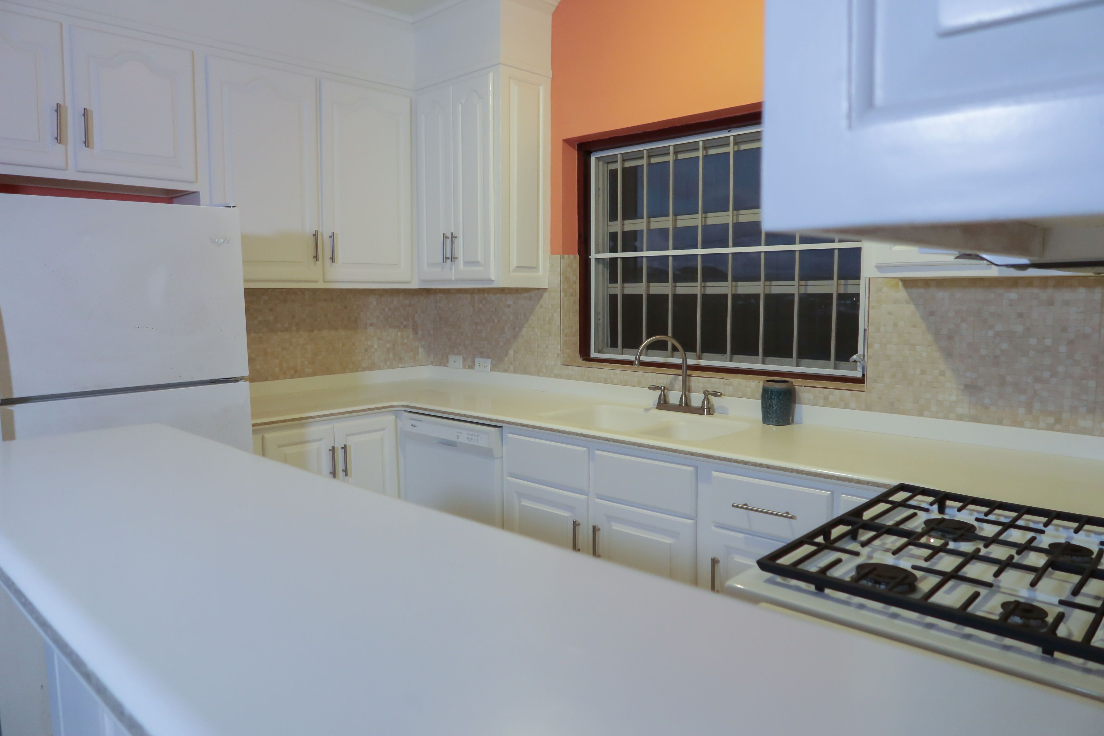 A kitchen with white cabinets, a window, and a gas stove.
