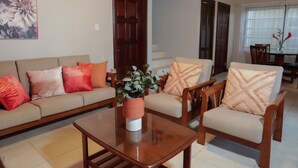 A living room with a sofa, armchairs, a coffee table, and a dining area with a table and chairs. - Trilogy Villas (Falmouth Harbour)
