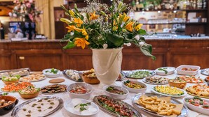 A buffet table with various dishes and a centerpiece of flowers. - Tenuta Elisabetta (Cecina)