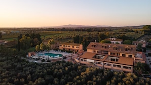 A large villa with a swimming pool, multiple buildings, and surrounding greenery. - Tenuta Elisabetta (Cecina)