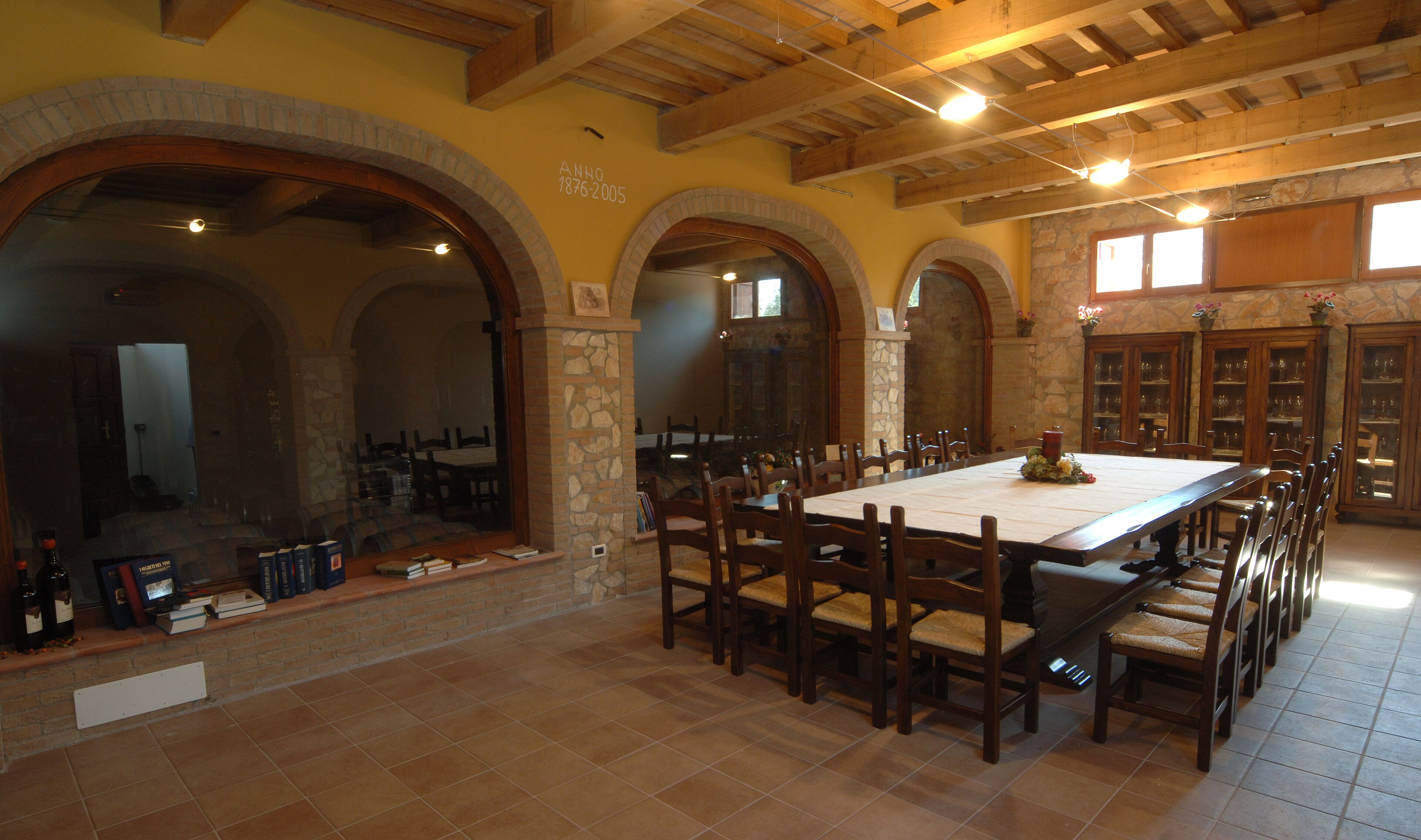 A spacious dining area with a long table, multiple chairs, and stone walls.