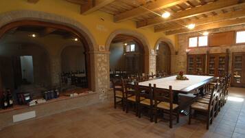 A spacious dining area with a long table, multiple chairs, and stone walls.