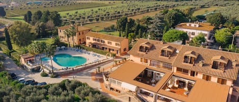 Una amplia villa con piscina, varios balcones y vistas al campo circundante.