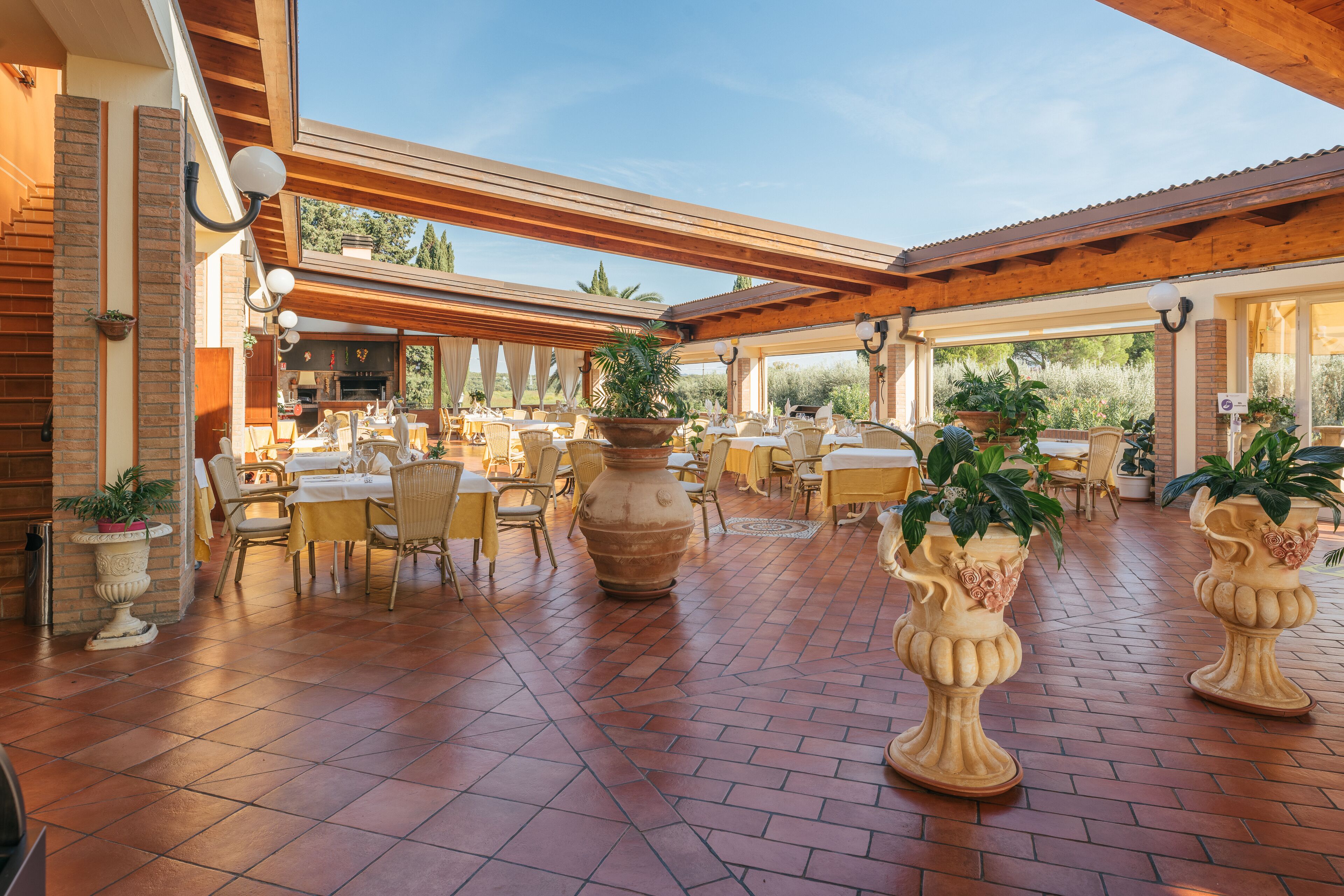 Un espace extérieur aménagé pour les repas, avec un sol en briques, des pergolas en bois et des plantes en pot.