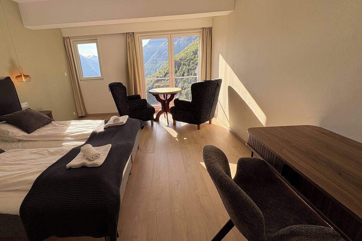 A hotel room with two beds, a small table, and two chairs.