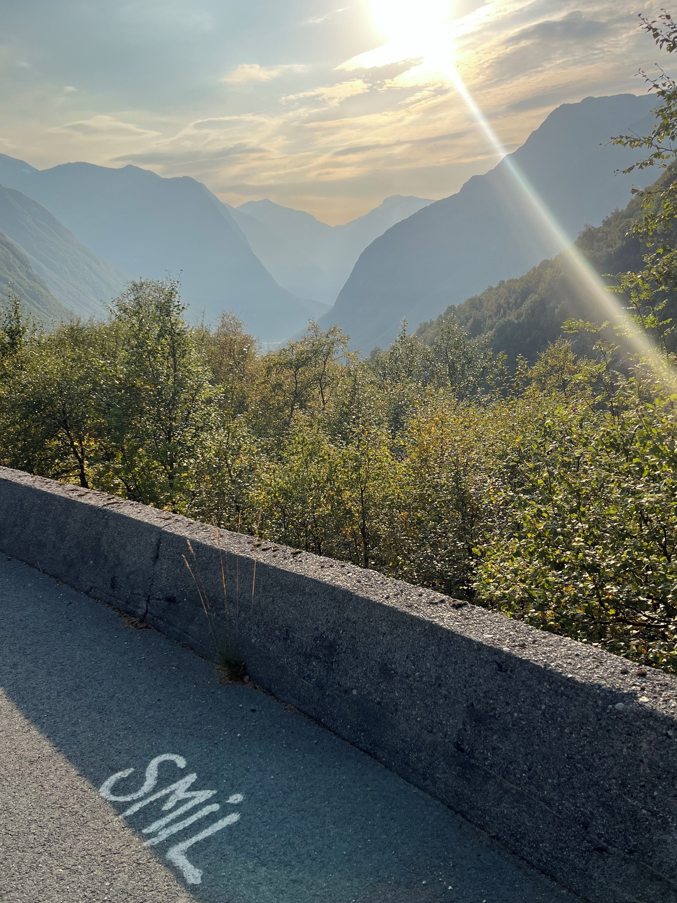 Une route bordée d’une barrière en béton et sur laquelle est inscrit un message peint.