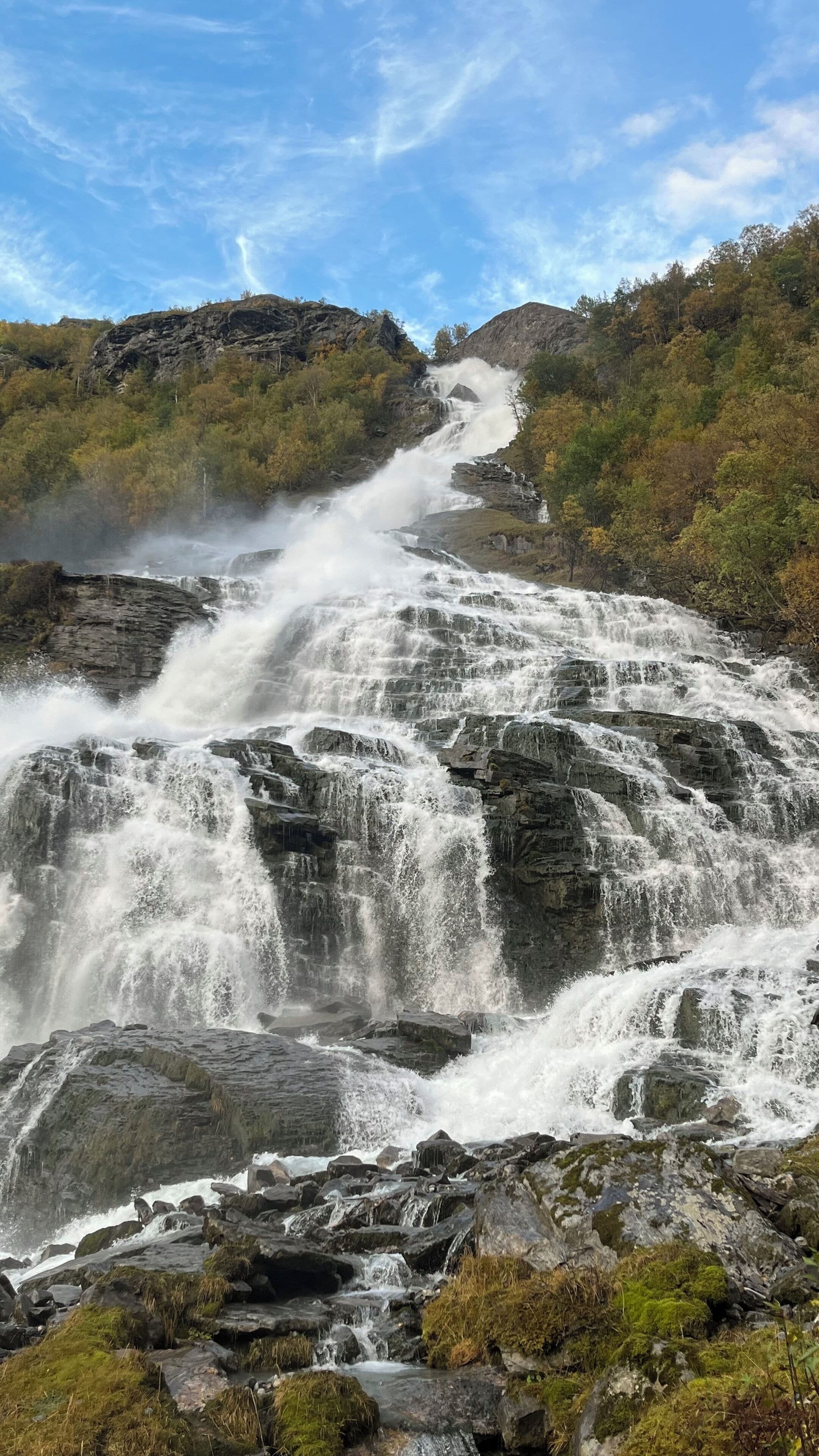 A waterfall cascading over rocky terrain surrounded by lush greenery.