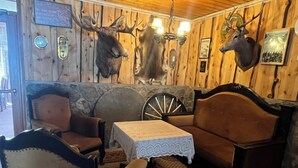 A rustic interior with wooden walls, a stone fireplace, a leather sofa, and a wooden rocking chair. - Hotel Videseter (Stryn)