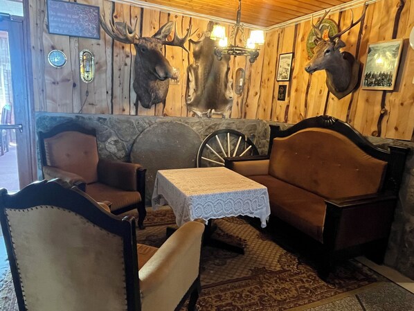 A rustic interior with wooden walls, a stone fireplace, a leather sofa, and a wooden rocking chair. - Hotel Videseter (Stryn)