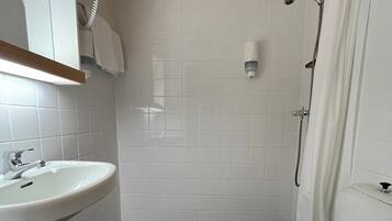A bathroom with a white sink, toilet, and shower.