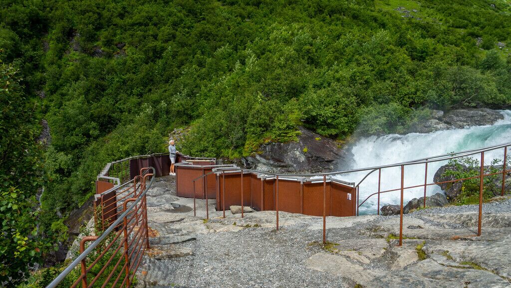 Eine felsige Aussichtsplattform mit Geländer, die auf einen Wasserfall blickt.