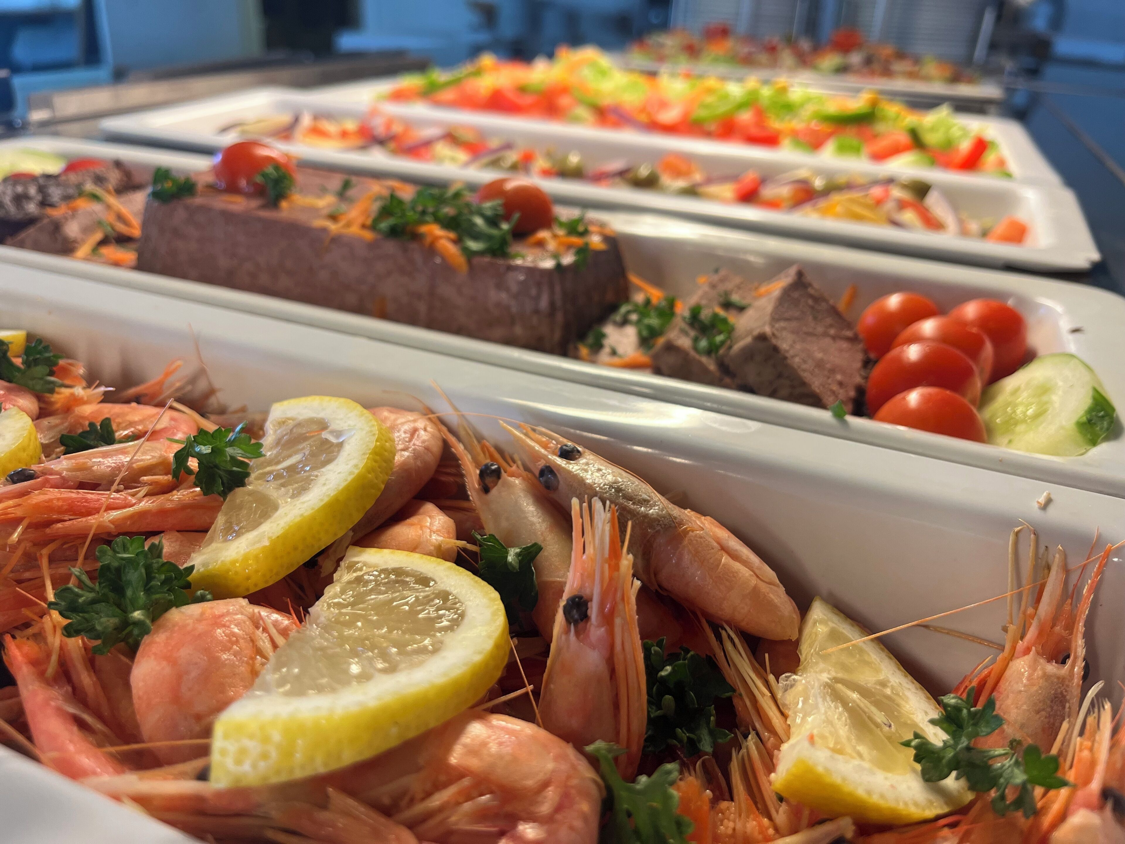 A buffet with seafood, including shrimp and lobster, garnished with lemon slices and parsley.