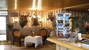 A wooden interior with a stone fireplace, a table with a candle, and a display of postcards. - Hotel Videseter (Stryn)