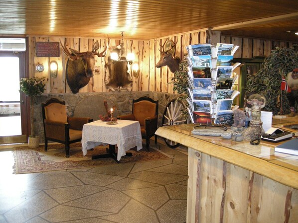 Un intérieur en bois avec une cheminée en pierre, une table éclairée par une bougie et une collection de cartes postales.