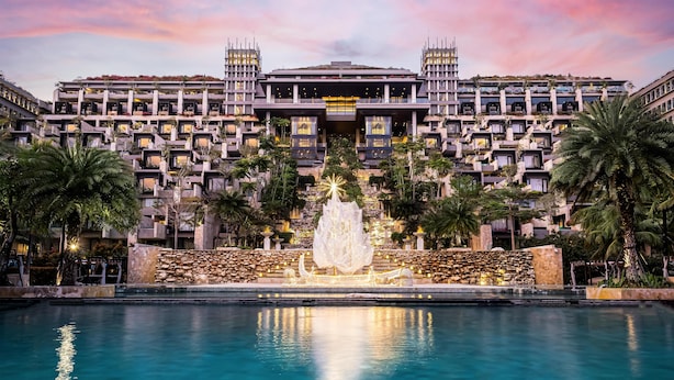 Un hôtel moderne doté d’une fontaine centrale, d’une piscine et d’un immeuble à plusieurs étages avec des balcons.