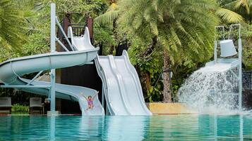 A water slide with a pool and palm trees in the background.