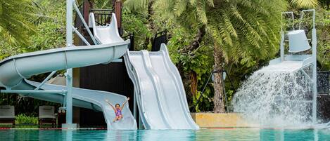 A water slide with a pool and palm trees in the background.