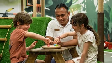Una mesa de madera con una etiqueta de nombre, un niño con una camiseta roja y una niña con un vestido blanco.