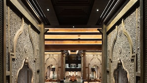Un hall d’entrée luxueux, agrémenté de boiseries décoratives, d’une fontaine centrale et d’un grand échiquier.