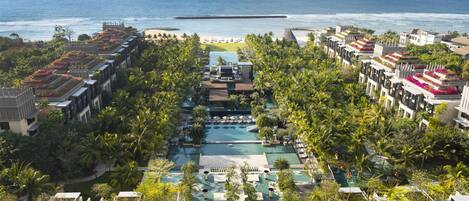 Un resort con piscina central, diversas zonas de natación y vistas al océano.