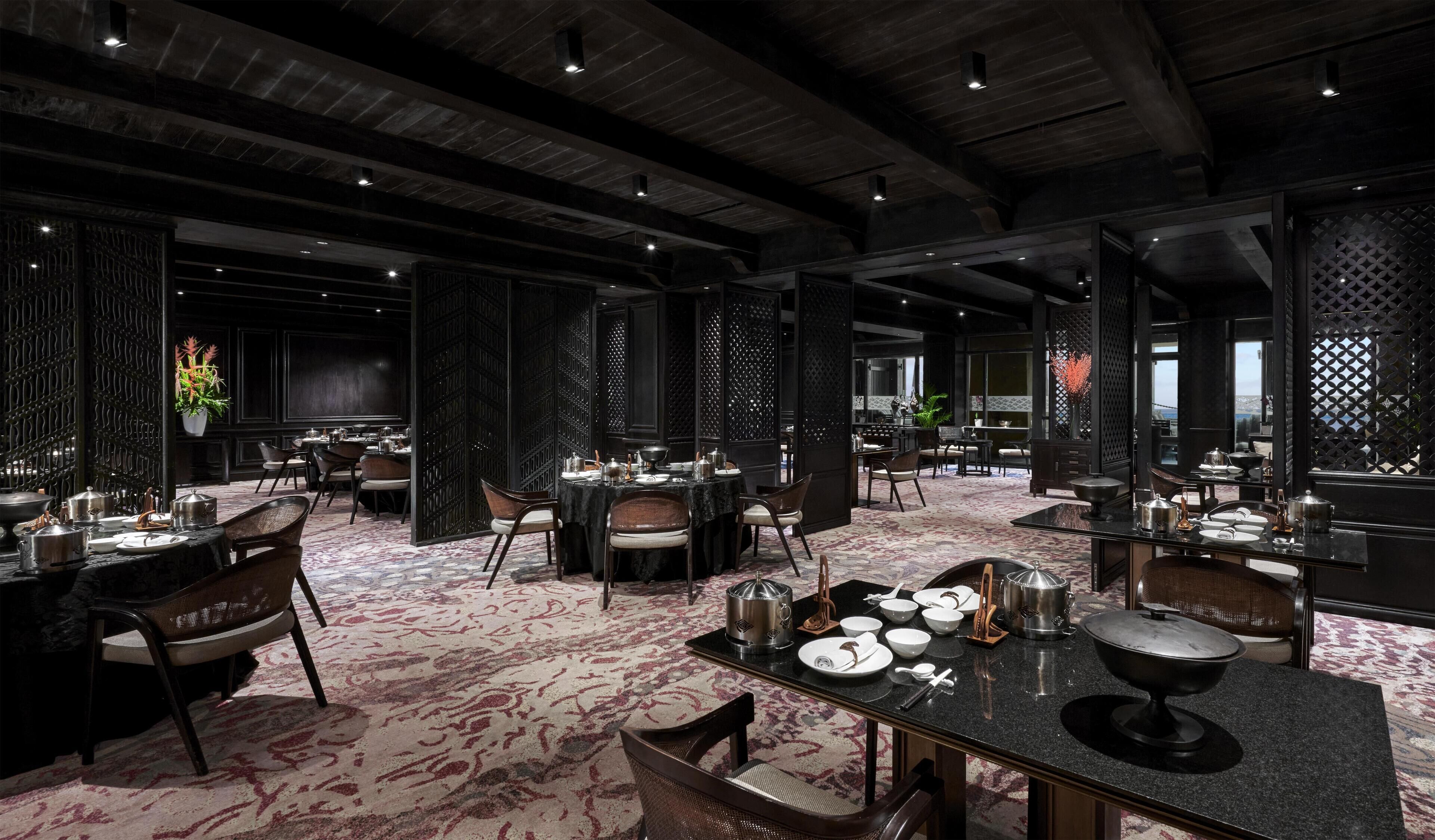 A restaurant with multiple dining tables, dark wood paneling, and a patterned carpet.