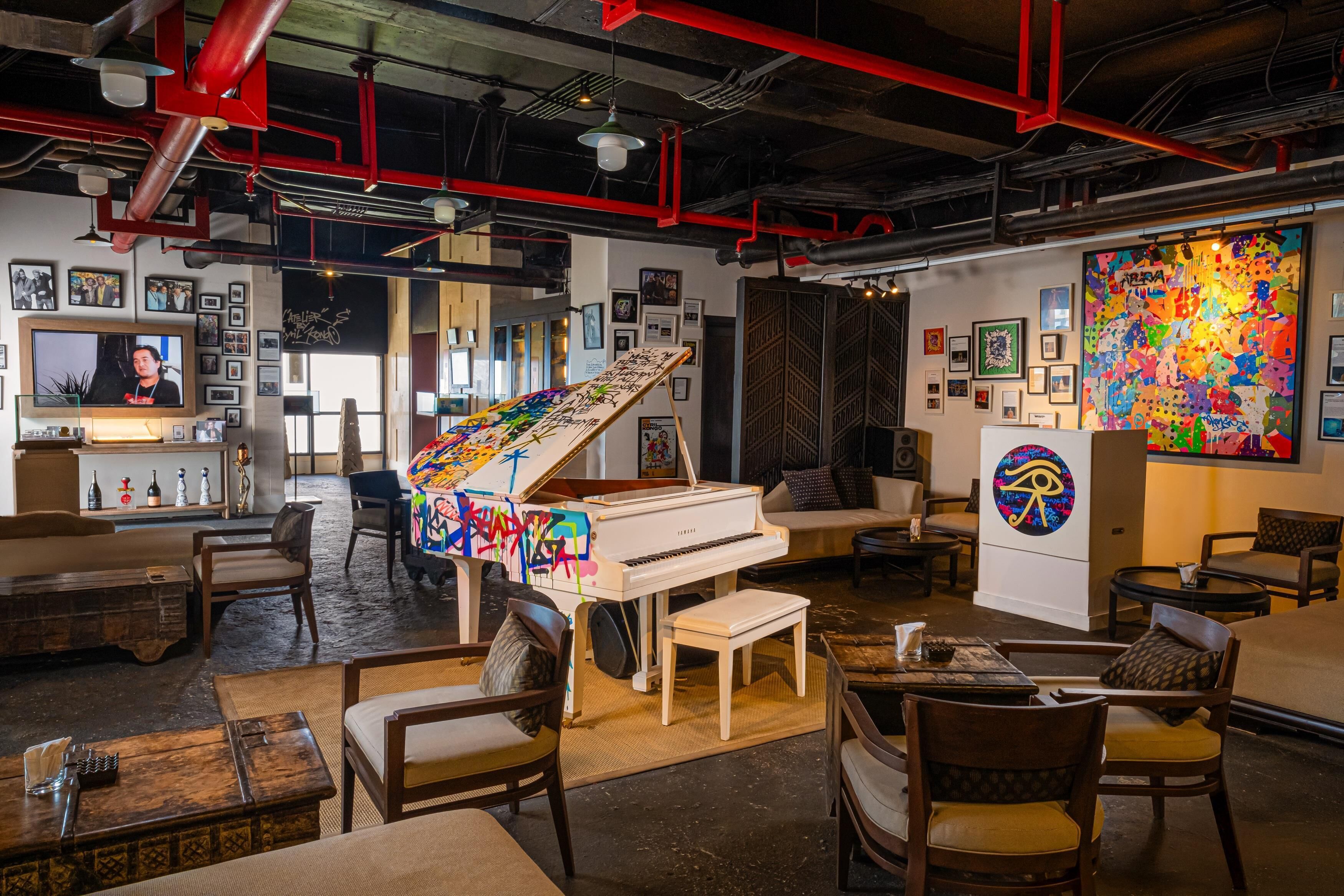 Una habitació àmplia amb un piano gegant, seients còmodes i un mural gran i colorit.