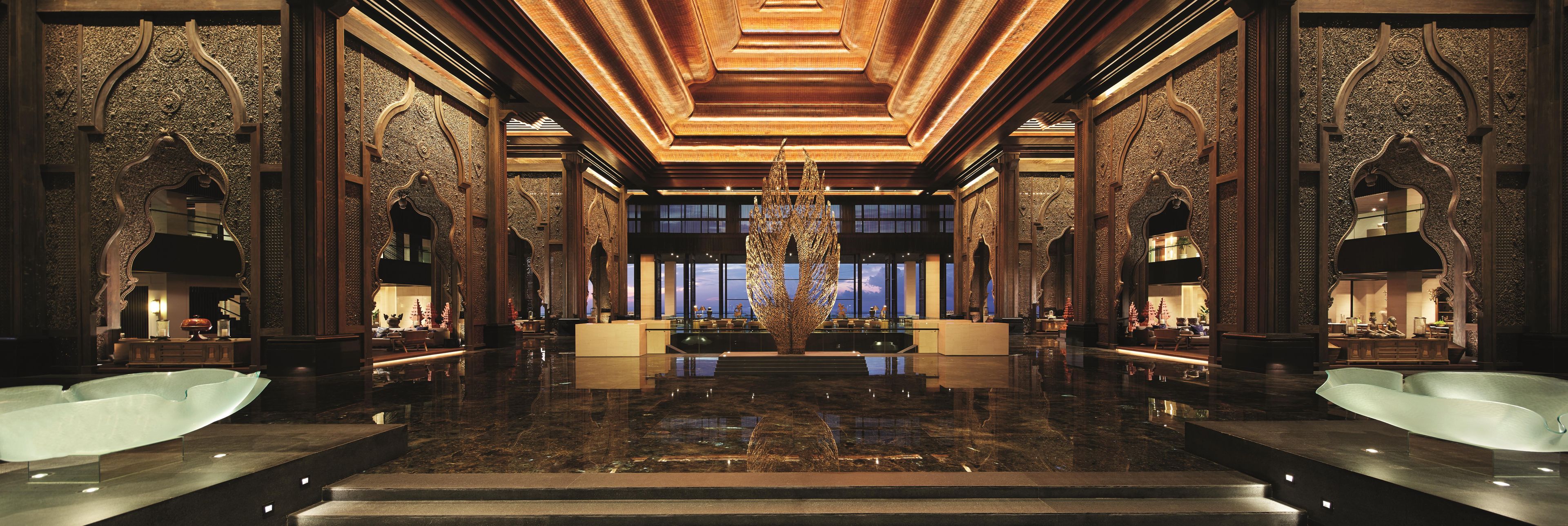 A luxurious lobby with a reflective marble floor, ornate wood paneling, and a grand chandelier.