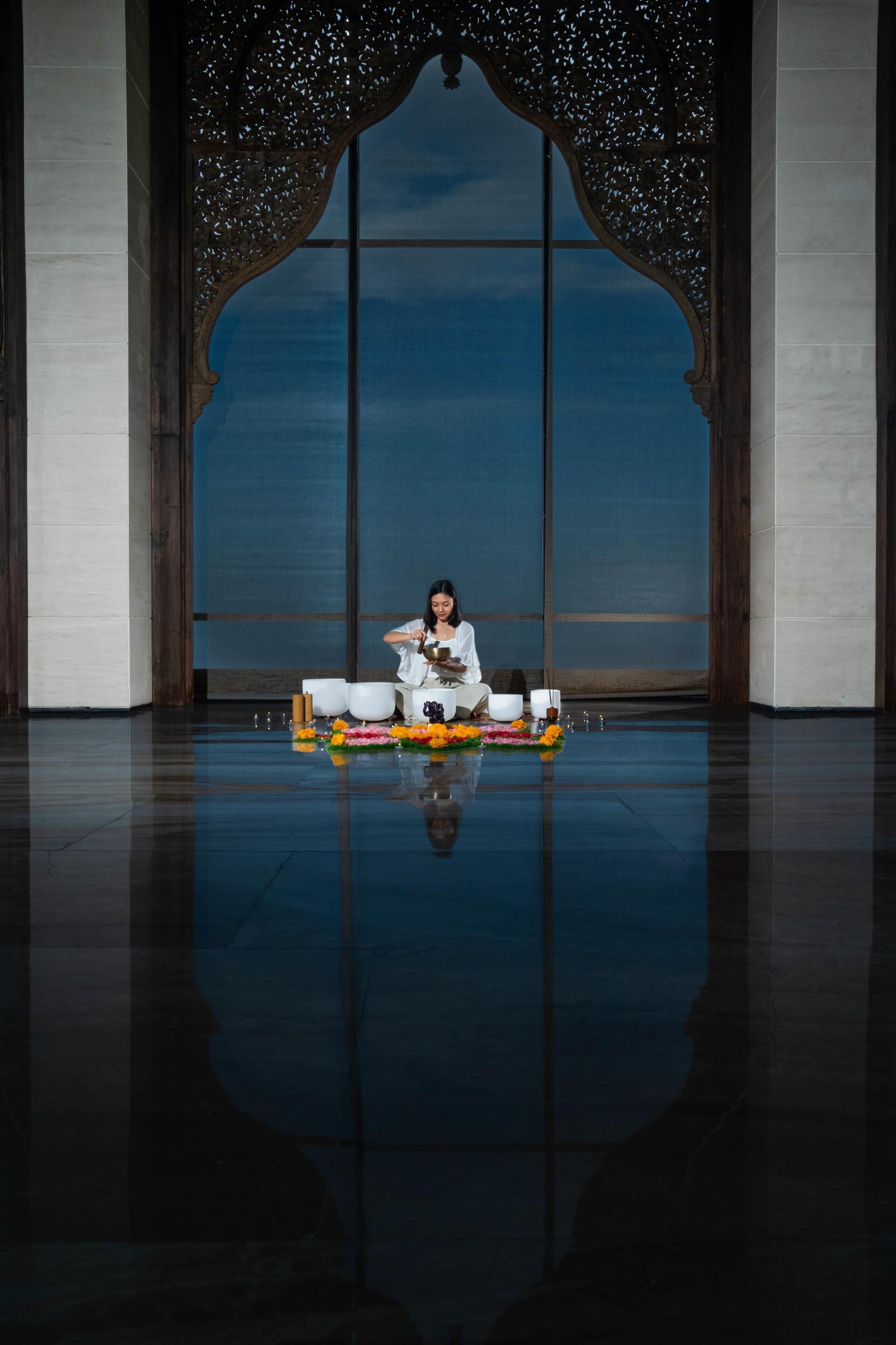 A person seated on a floor with a table in front of a large window.