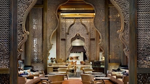 An ornate interior with a central seating area, high ceilings, and intricate wall designs.