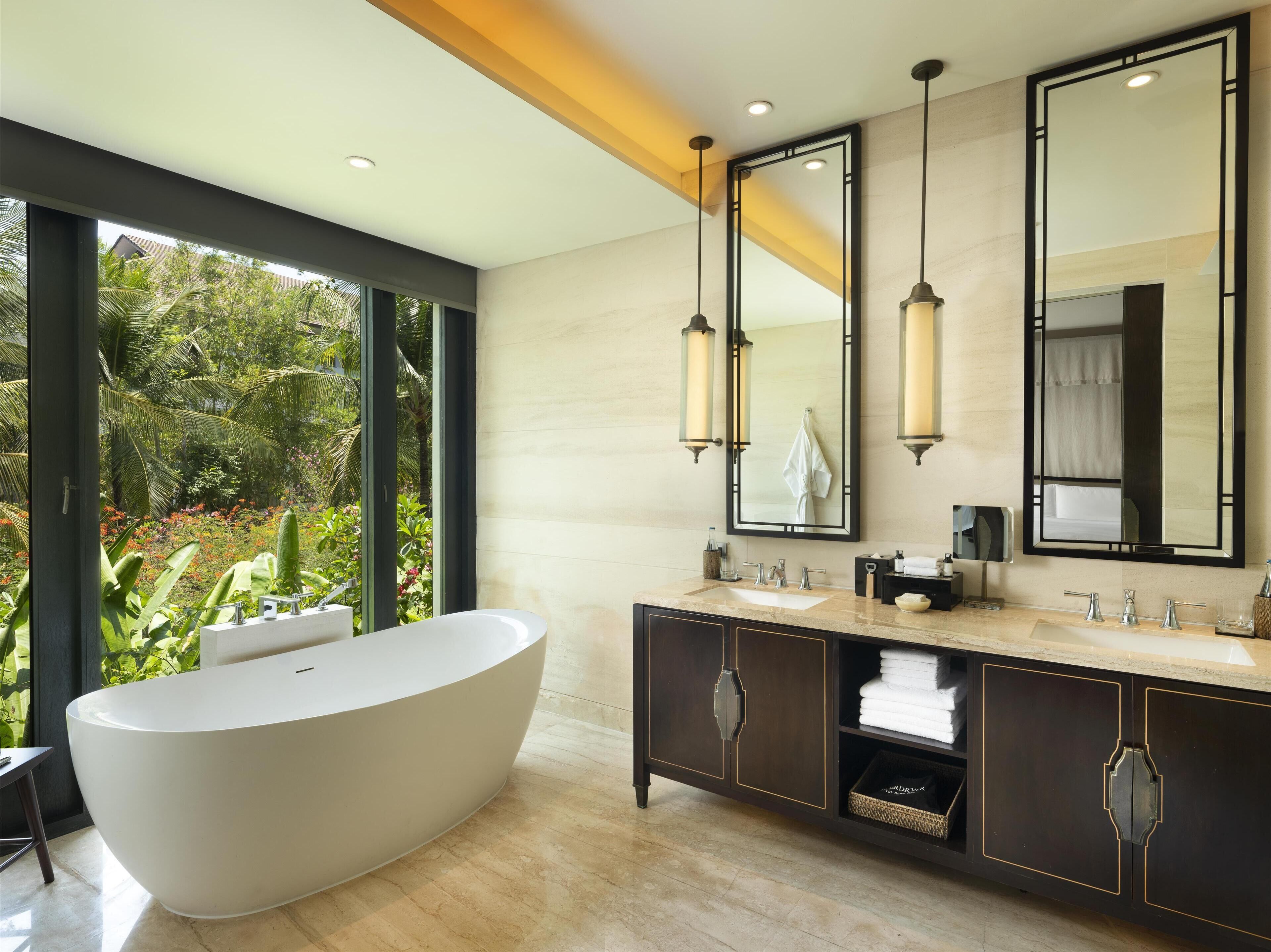 A modern bathroom with a freestanding bathtub, dual sinks, and large mirrors.