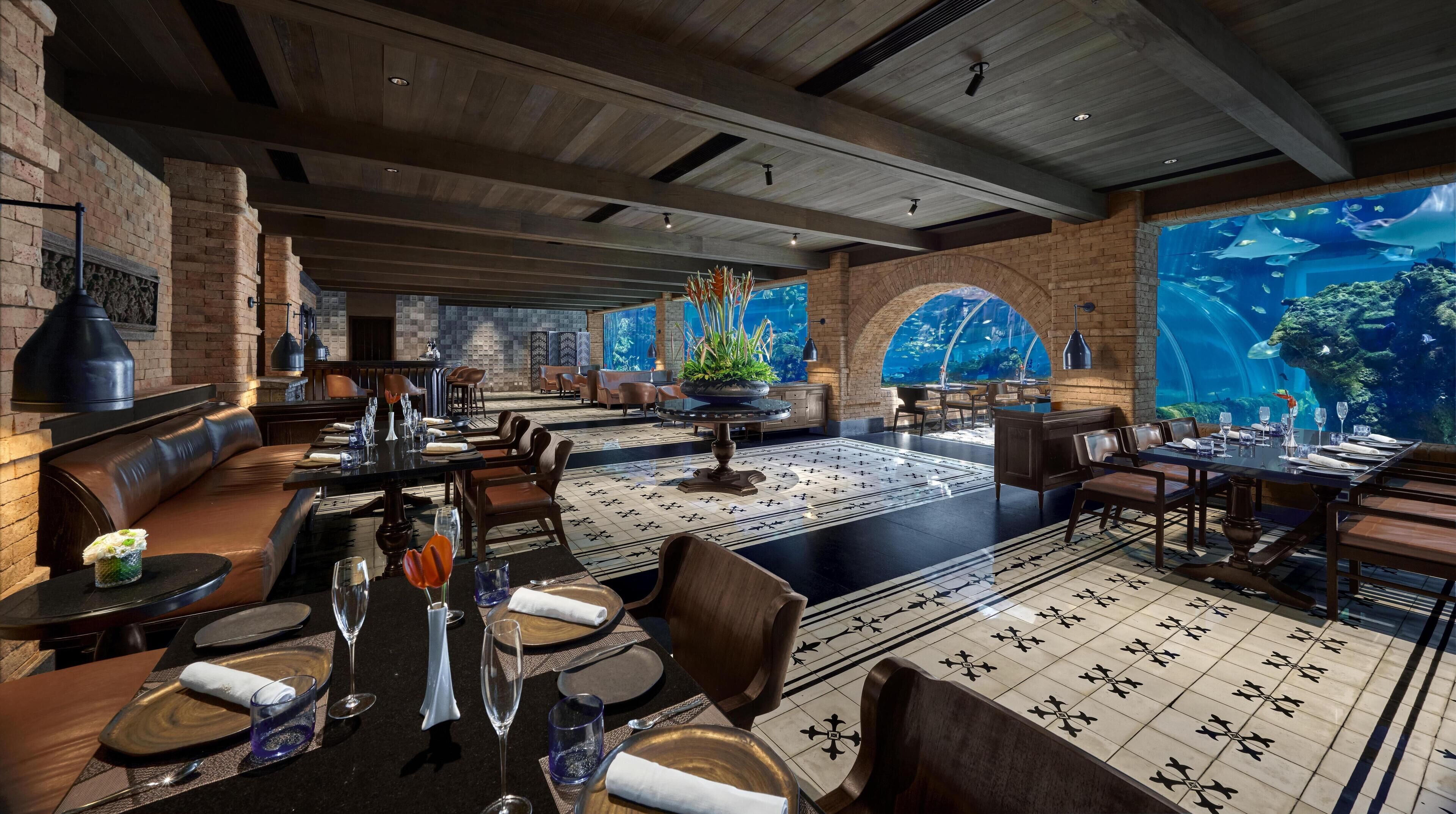 A restaurant with a large aquarium, brick walls, and a modern interior design.