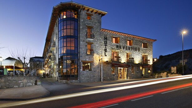 A stone building with a modern design, featuring a prominent tower and large windows.