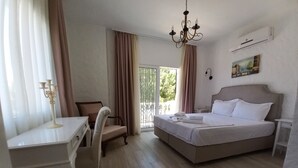 Une chambre d’hôtel avec un lit, un bureau, une chaise, un lustre et un tableau au mur.