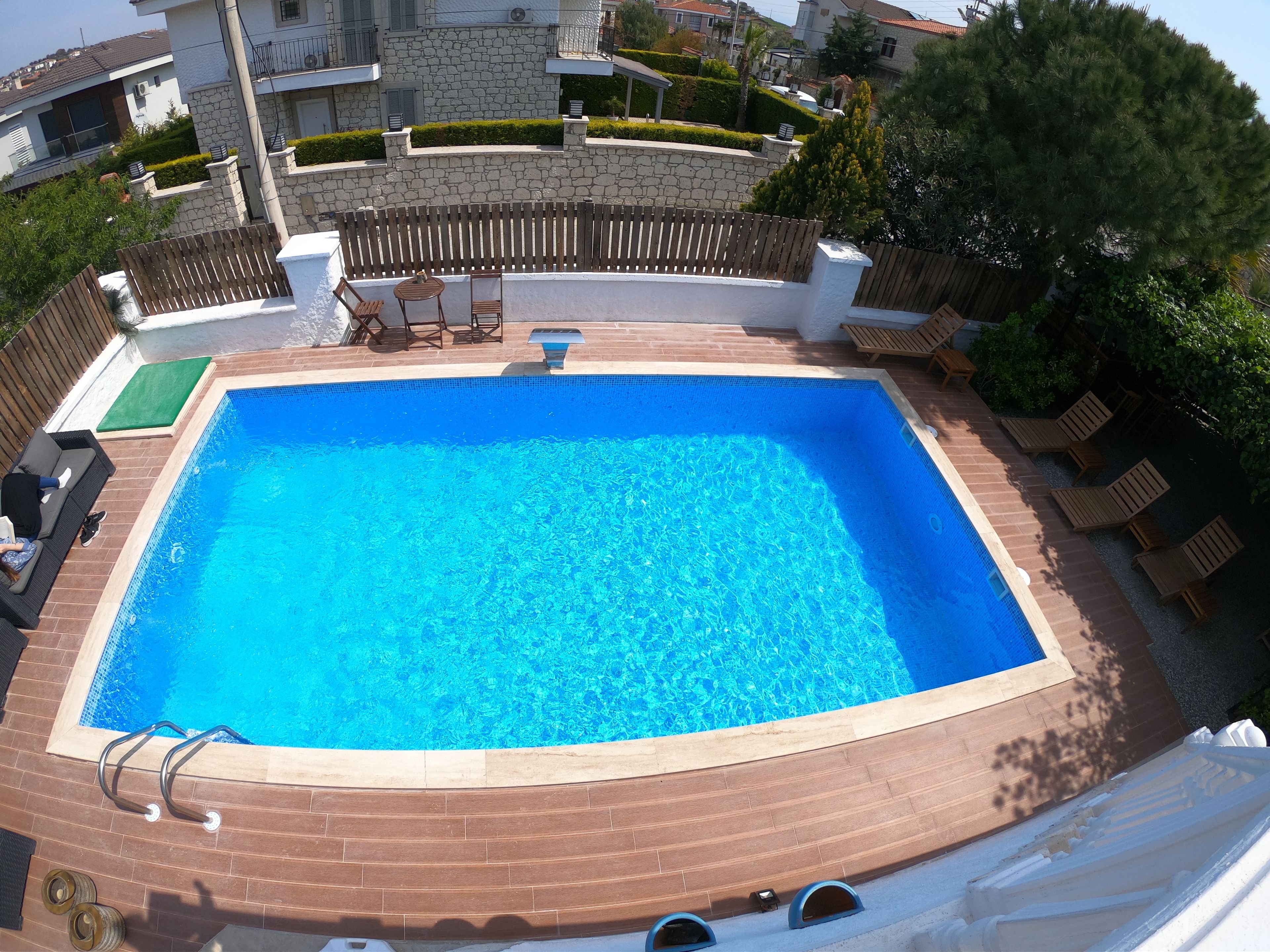 Una piscina al aire libre, sombrillas, sillones reclinables de piscina