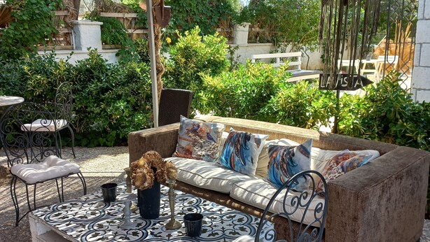 Un espace extérieur aménagé avec une table à motifs, un canapé rembourré et des chaises en métal.