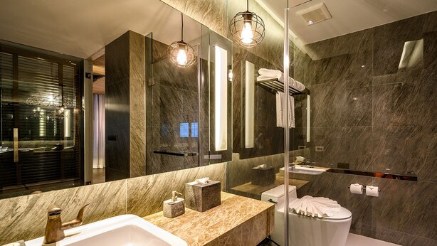 A modern bathroom with a large mirror, marble walls, a glass shower enclosure, and a white sink with a marble countertop. - Kalima Resort & Villas Khaolak (Thai Mueang)
