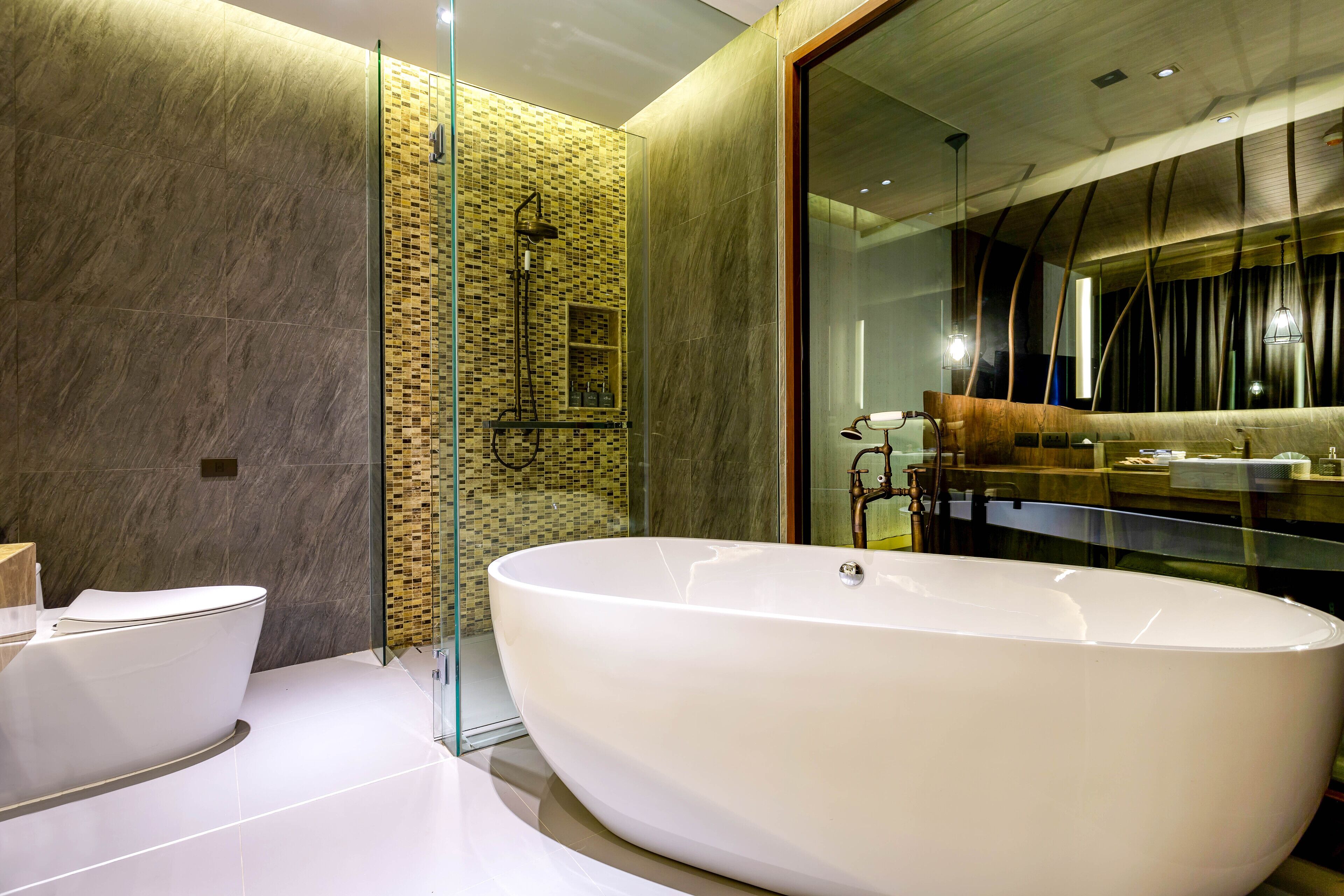 Un baño moderno con una bañera independiente, una ducha con cerramiento de vidrio y un revestimiento de mármol.