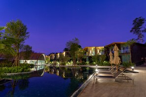 A nighttime resort pool area with a clear view of the pool, lounge chairs, and surrounding buildings. - Kalima Resort & Villas Khaolak (Thai Mueang)