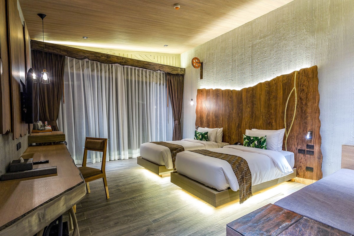A hotel room with two beds, a desk, and a chair.