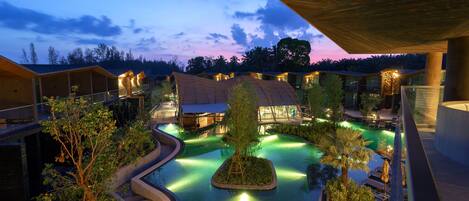 A resort with a swimming pool, covered walkways, and a sunset view.