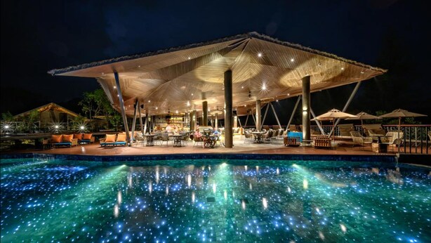 A nighttime pool area with a covered seating area and lounge chairs. - Kalima Resort & Villas Khaolak (Thai Mueang)