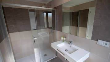 A modern bathroom with a glass-enclosed shower, a white sink, and a large mirror.