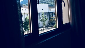 Ein Fenster mit Blick auf Berge und Gebäude.