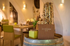 L’intérieur d’un restaurant est agrémenté d’un élément décoratif central en forme de tonneau en bois, d’un vase vert contenant une plante et d’un panneau d’affichage en liège.