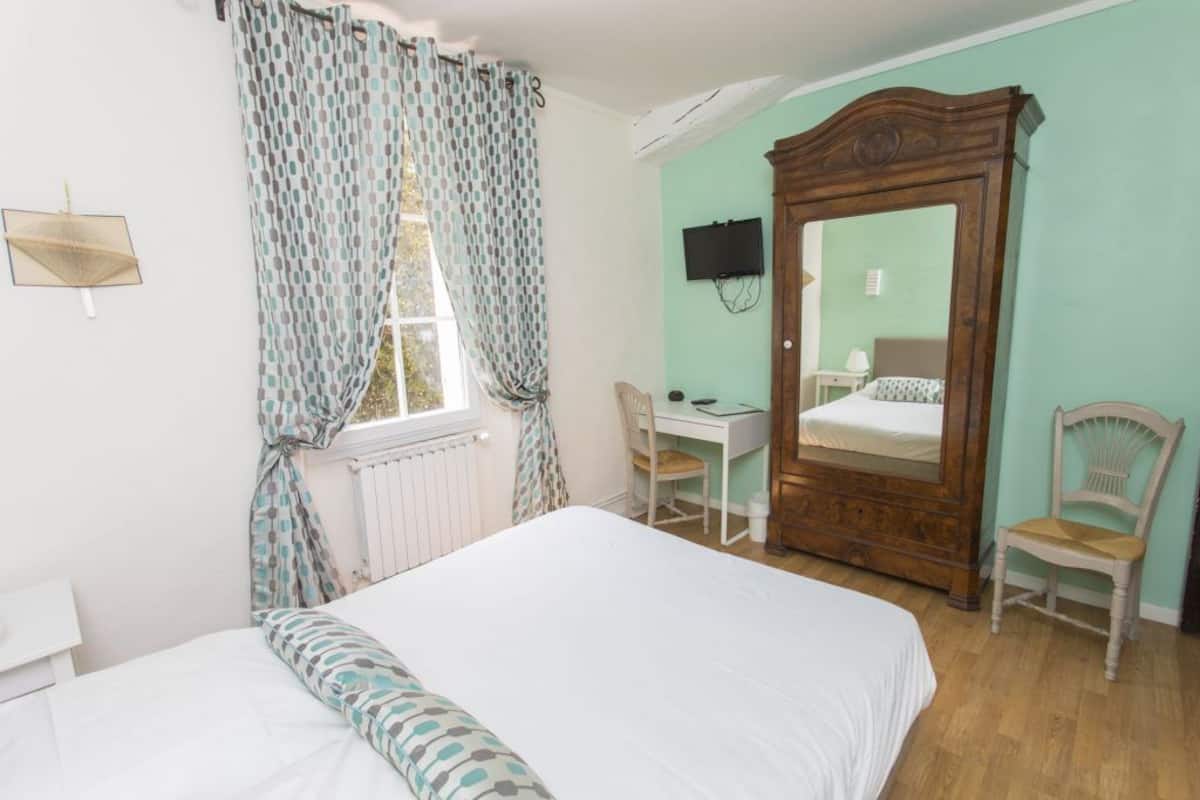 Une chambre à coucher avec un lit, un bureau, une chaise, une armoire et un téléviseur fixé au mur.