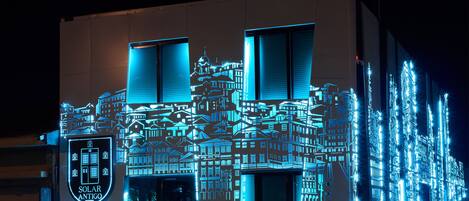 A building facade with a geometric light projection of a cityscape, including a prominent 'SOLAR ANTIGO PORTO' sign.