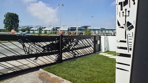 A modern building with a glass facade and a parking area with a black metal fence.