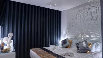 A modern hotel room with a large bed, dark curtains, and a wall mural.