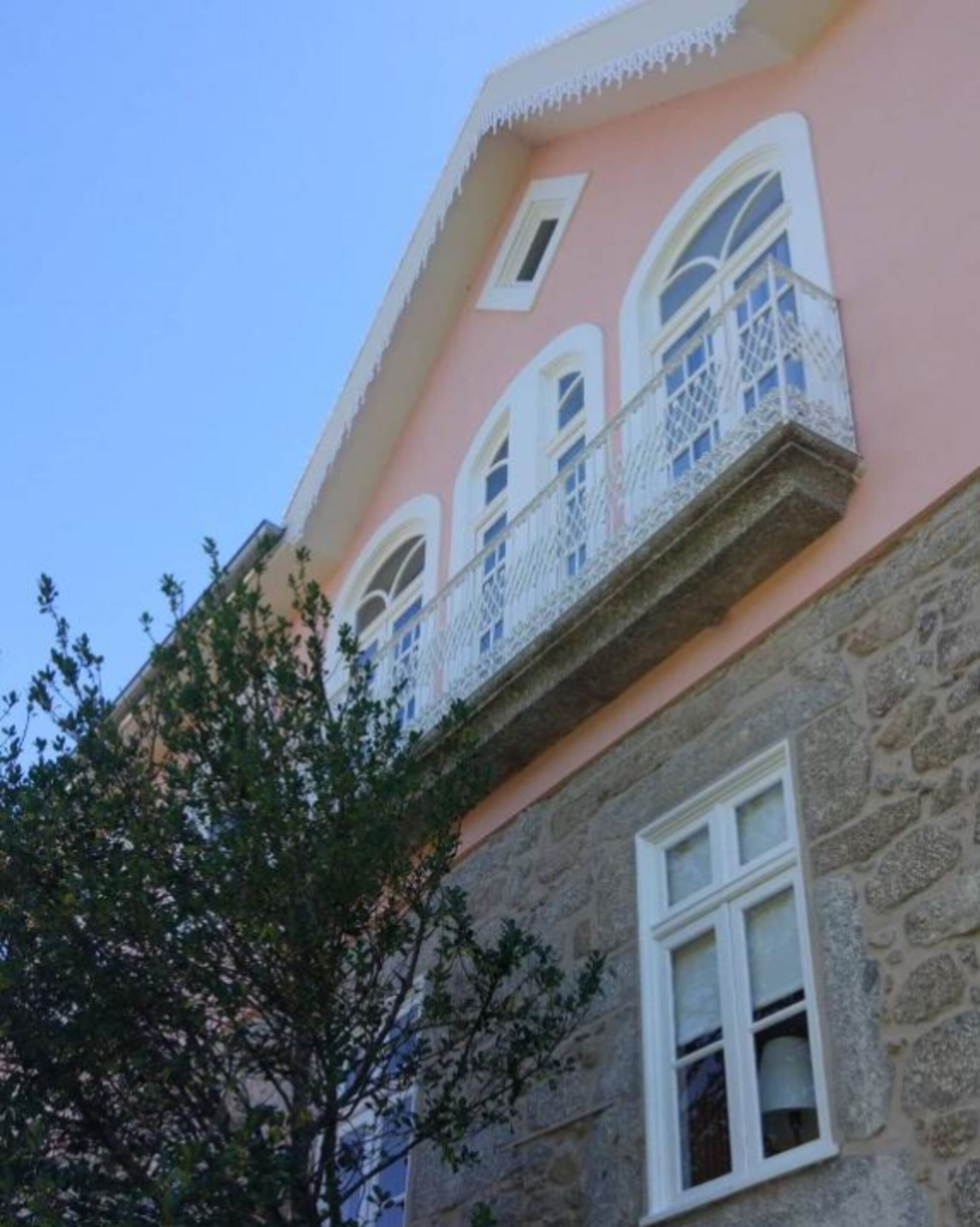 A pink building with white-framed windows and a stone base.