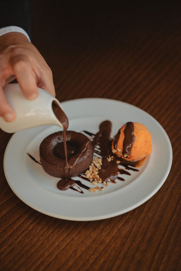 A dessert on a plate with chocolate sauce being poured over it. - Ribeira Collection Hotel by Piamonte Hotels (Arcos de Valdevez)